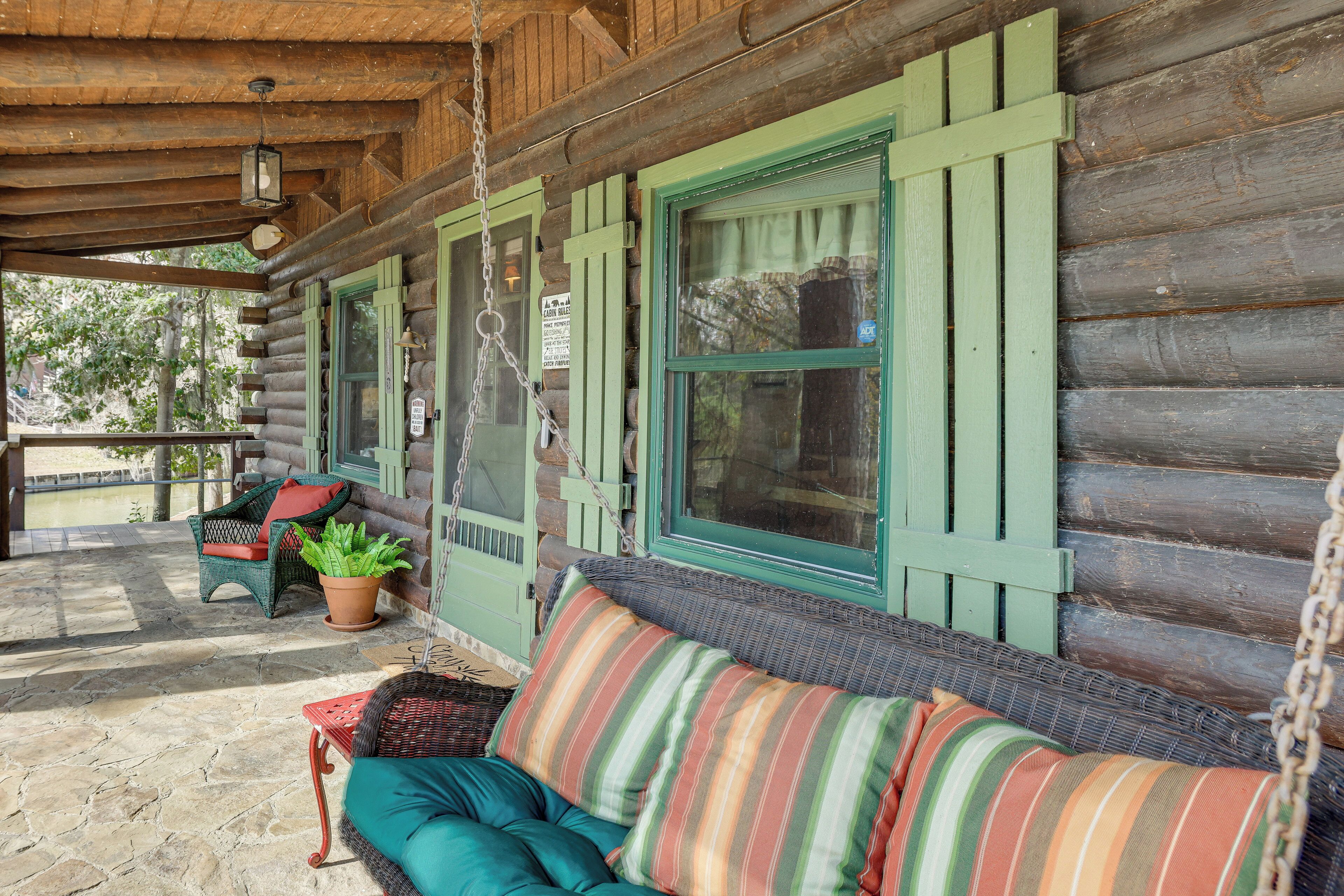 A log cabin with a porch, wicker furniture, and a hanging lantern.