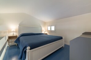 Ein Schlafzimmer mit Bett, Nachttischen, einem Fenster und einer Treppe.