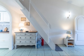 A staircase leading to a landing with a white wall, a small table with a lamp, and a door. - Il Portolano 15 - Goelba (Porto Azzurro)