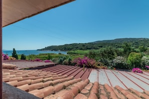 A terrace with terracotta tiles, a view of the sea, and lush greenery. - Il Portolano 15 - Goelba (Porto Azzurro)