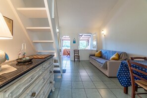 Un amplio espacio de estar con un sofá, una mesa de comedor y una escalera.