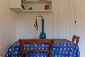 Ein Esstisch mit blauer Tischdecke, einem grünen Blumenvasen und einem Holzsessel.