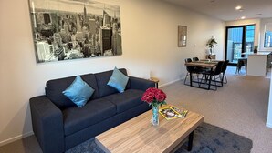 En moderne stue med sofa, sofabord og et bybillede som maleri.