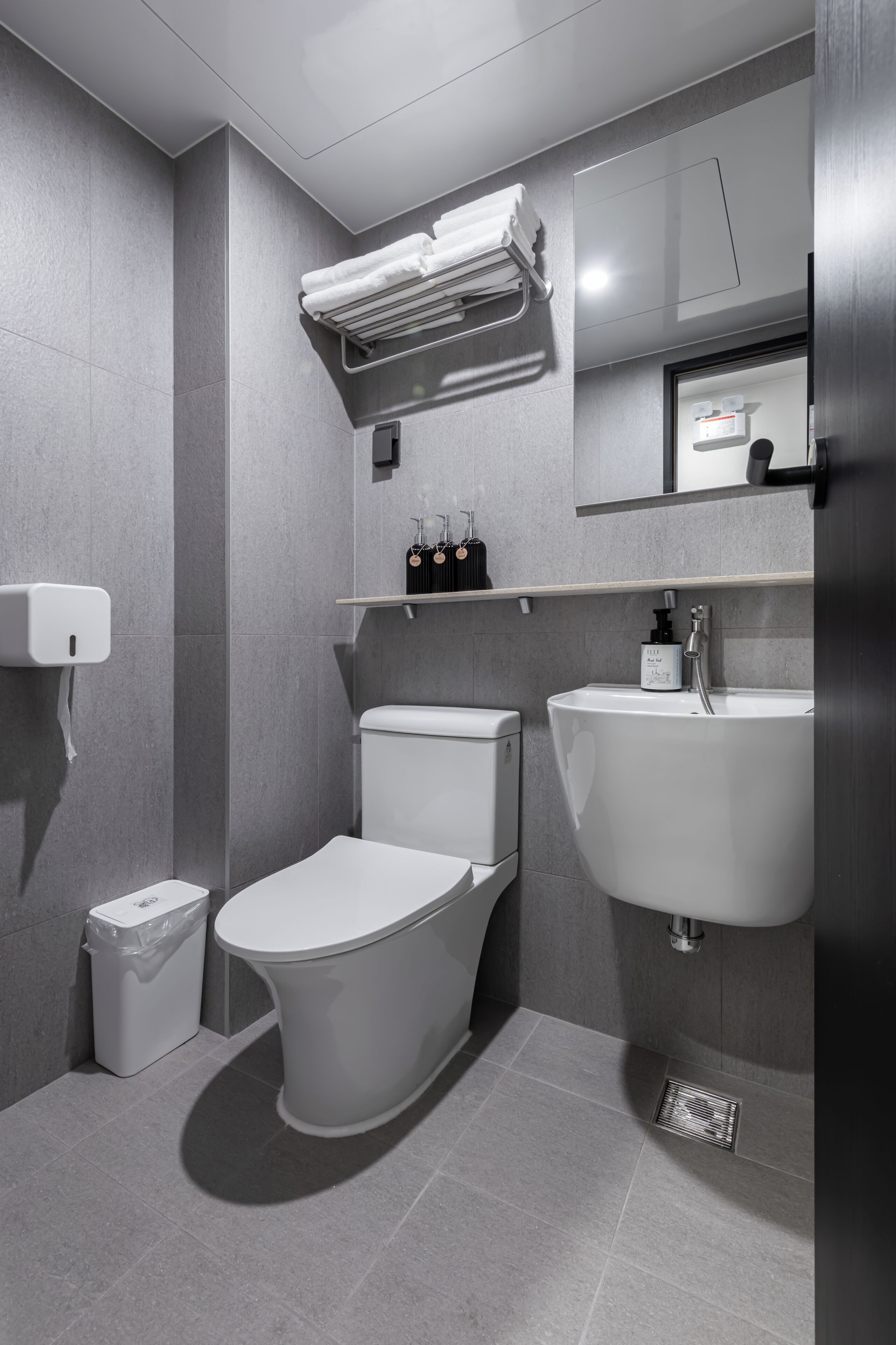 Un baño moderno con inodoro, lavamanos y toallero.