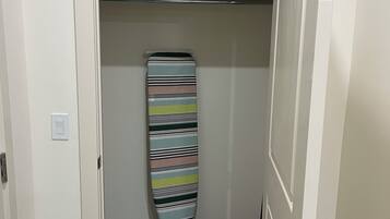 Un couloir avec un placard contenant une planche de surf à rayures et un sac bleu.
