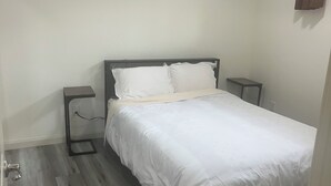 A bedroom with a bed, bedside tables, and a wooden floor. - 3 BdR Suite in Calgary - Enjoy Rockies, Banff, Lake Louise, Dinosaur museum (Calgary)