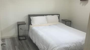 Une chambre à coucher avec un lit, des tables de chevet et un plancher en bois.