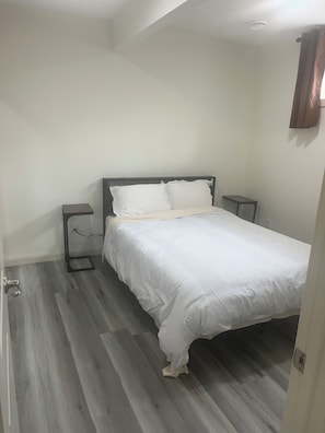 Ein Schlafzimmer mit einem Bett, Nachttischen und Holzboden.