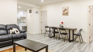 A living room with a sofa, a coffee table, and a dining area with a table and chairs. - 3 BdR Suite in Calgary - Enjoy Rockies, Banff, Lake Louise, Dinosaur museum (Calgary)