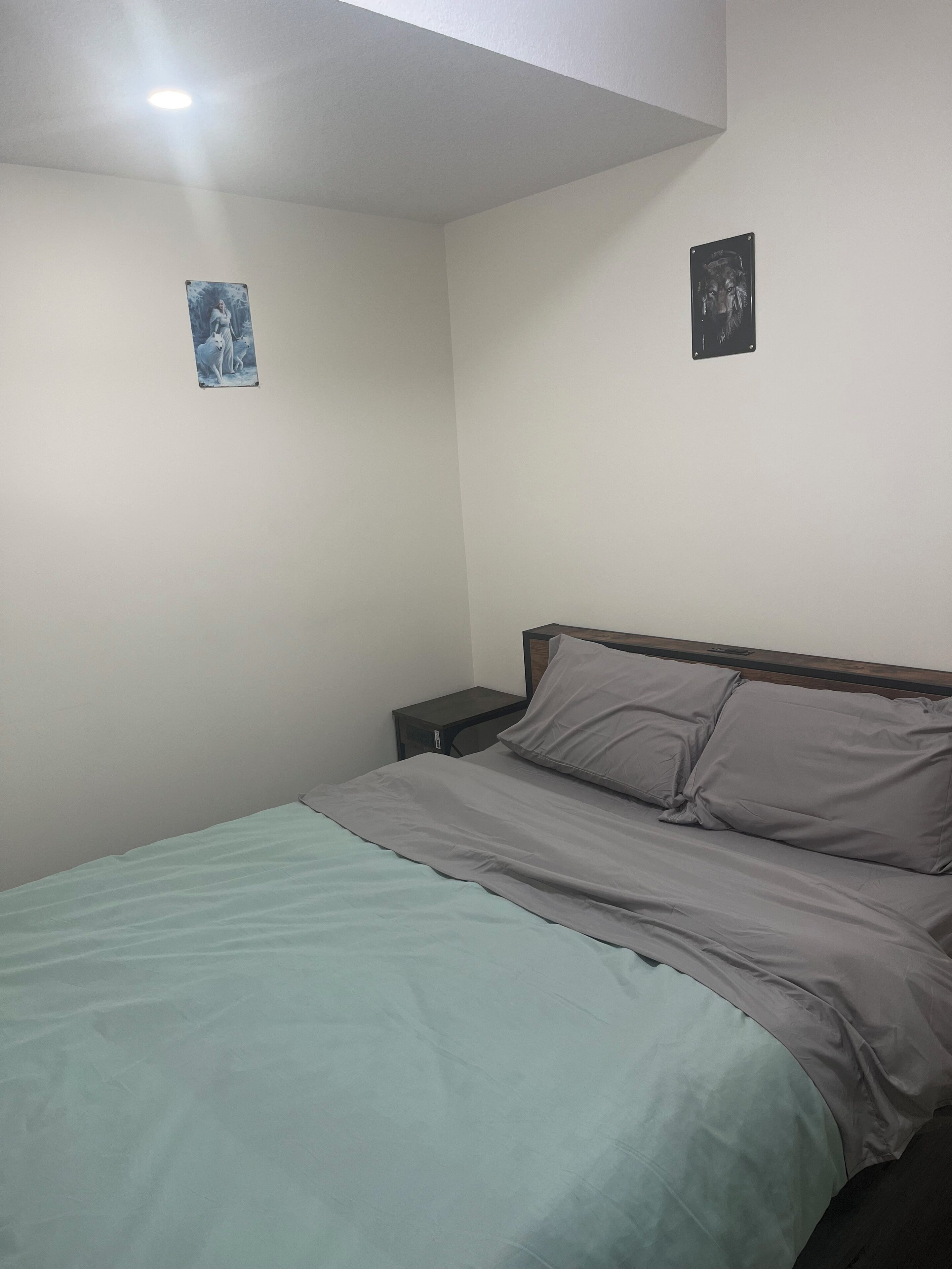 Une chambre à coucher avec un lit, une table de chevet et deux tableaux accrochés au mur.