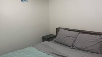 Une chambre à coucher avec un lit, une table de chevet et deux tableaux accrochés au mur.
