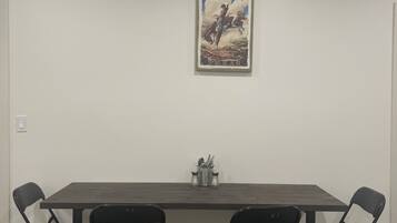 Une salle de conférence avec une longue table, quatre chaises et un tableau représentant un cow-boy à cheval.