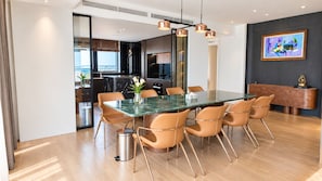 A modern dining area with a glass-top table, six chairs, and a trash bin. - Tra Co Long Beach Hotel & Resort (Mong Cai)