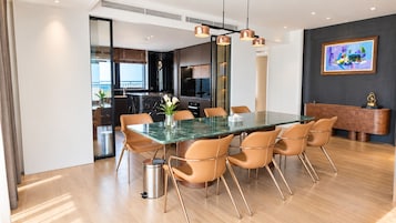 A modern dining area with a glass-top table, six chairs, and a trash bin.