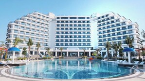 A large hotel with multiple floors, a central pool, and palm trees. - Tra Co Long Beach Hotel & Resort (Mong Cai)
