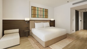 A modern hotel room with a large bed, bedside tables, a wall-mounted artwork, and a door leading to another room. - Tra Co Long Beach Hotel & Resort (Mong Cai)