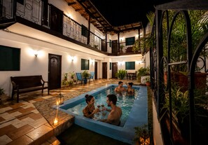 A pool area with a checkered floor, a bench, and potted plants. - Hospedaje valeria (Granada)