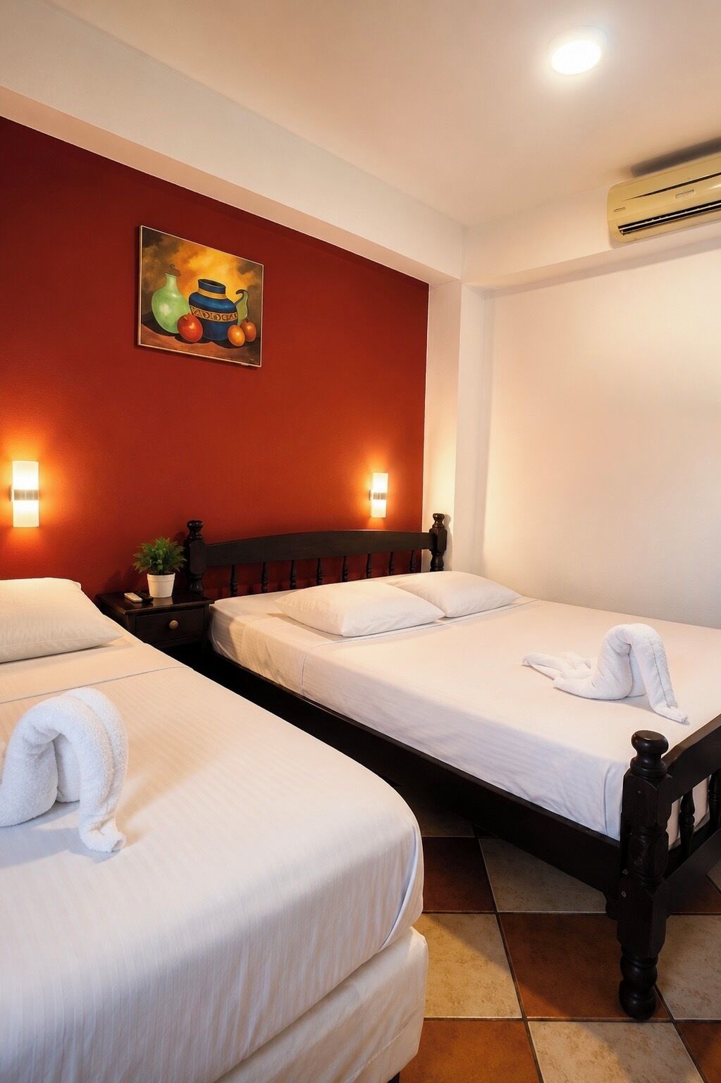 Une chambre d’hôtel avec deux lits, un tableau au mur et un appareil de climatisation.
