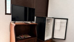 Un espace de vie compact comprenant une télévision, un petit réfrigérateur et un meuble en bois.