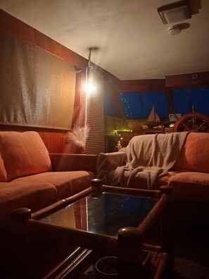 A cozy room with a glass coffee table, wooden furniture, and a view of the night sky. - 3-bedroom boat in cool Key West with air conditioning (Key West)