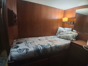 Una habitación de hotel con una cama, una mesita de noche, una lámpara y un panel de pared de madera.