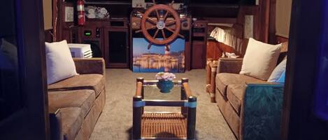 A cozy living room with a central coffee table, two sofas, and a decorative wheel.