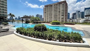 Ein Pool auf dem Dach mit Stadtansicht im Hintergrund, umgeben von Grünflächen und modernen Geb äuden.