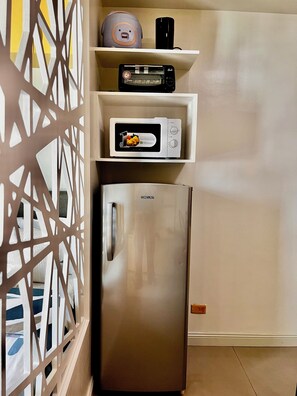 Eine Küche mit einem Edelstahl-Kühlschrank, einer Mikrowelle und einem Toaster auf einer Ablagefläche.