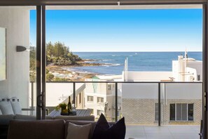 Ein Balkon mit Meerblick, ein weißes Gebäude und eine Couch mit Kissen.
