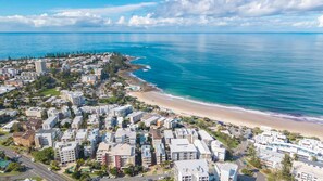 Un quartier résidentiel situé sur la côte, avec des propriétés donnant sur la plage et une route menant à la plage.