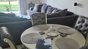 Un'area pranzo con un tavolo rotondo, sedie, sottopiatti e un oggetto decorativo.