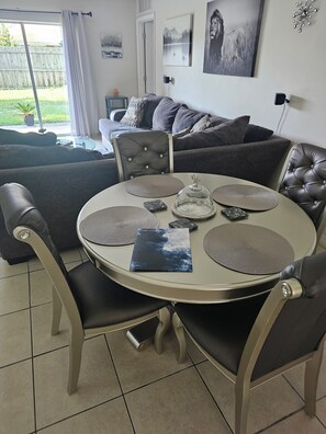 Een eetruimte met een ronde tafel, stoelen, placemats en een decoratief object.