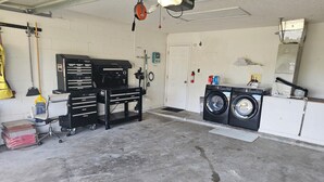 Un garage con un banco da lavoro, una lavatrice e una scopa.