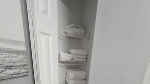 Un bagno con una porta bianca, un portascopino e uno scaffale con articoli da toilette.