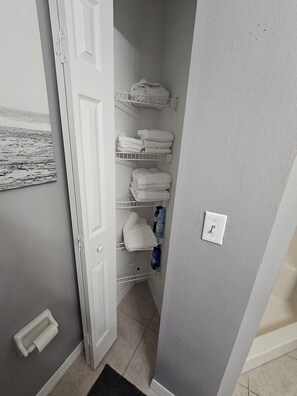 Een badkamer met een witte deur, een handdoekhouder en een plank met toiletartikelen.