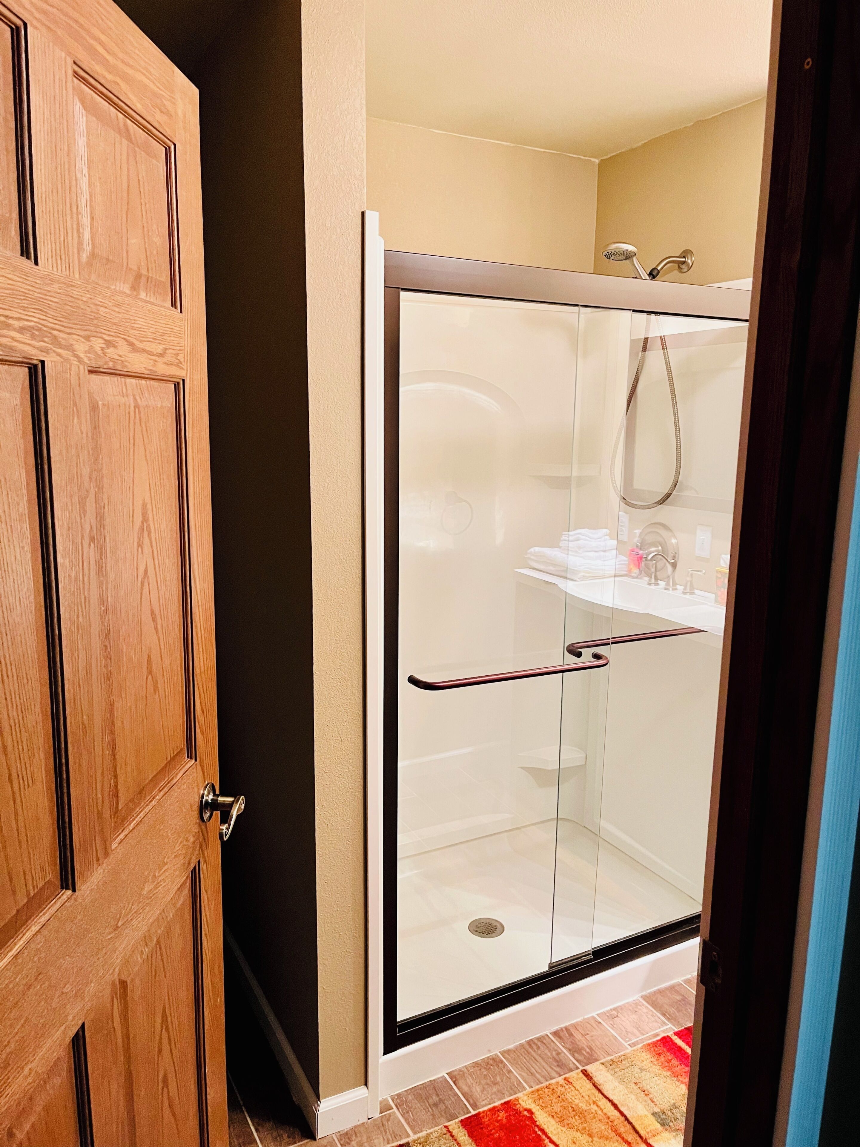 A glass-enclosed shower with a white sink and a towel rack.