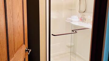 A glass-enclosed shower with a white sink and a towel rack.
