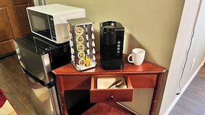 Eine Küchenzeile mit Mikrowelle, Kaffeemaschine und einem kleinen Schrank.