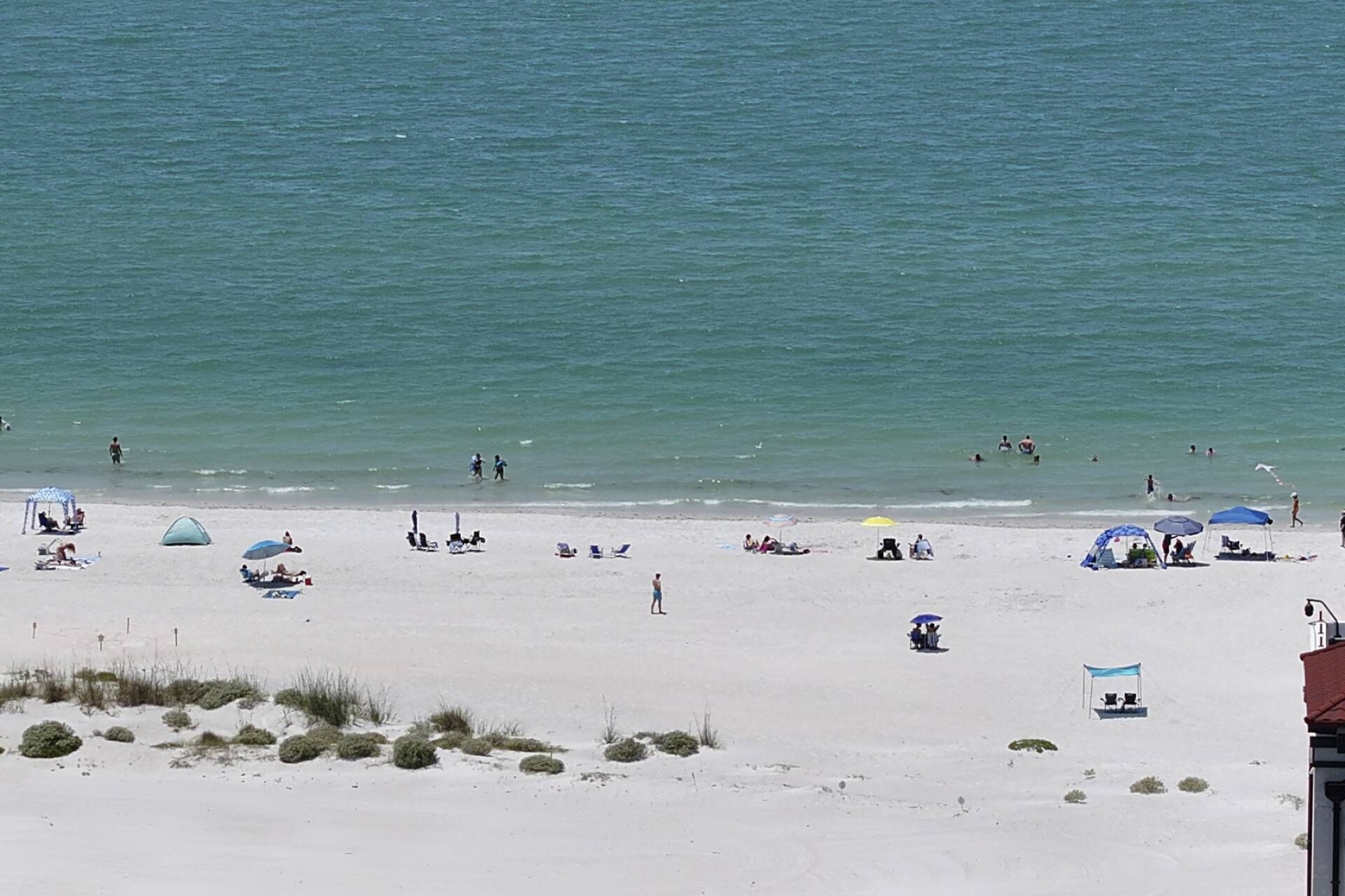 A beach with people, umbrellas, and beach chairs.