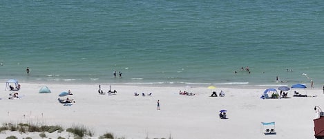 Ein Strand mit Menschen, Sonnenschirmen und Liegestühlen.