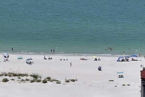 Ein Strand mit Menschen, Sonnenschirmen und Liegestühlen.