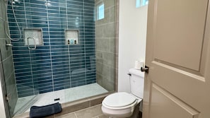 A bathroom with a glass shower enclosure, a white toilet, and a towel on the floor. - Guy’s Night Out - WinStar Bachelor - King Bed (Thackerville)