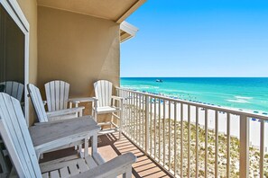 Ein Balkon mit weißen Adirondack-Stühlen und Blick auf den Strand.