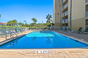 Ein Swimmingpool mit einer Tiefenmarkierung von 5 Fuß, umgeben von Liegestühlen und Palmen.