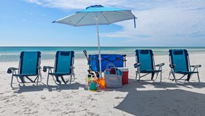 A beach scene with four blue beach chairs, a blue and white umbrella, a cooler, and beach toys. - Emerald Dunes 502•Updated•Beachfront•Pool +Hot Tub•Beach Gear•Nearby Dining (Destin)