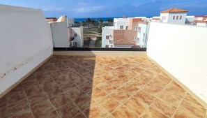 Terraço no telhado com vista para edifícios e céu claro.