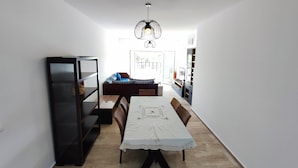 A compact living space with a dining area, a sofa, a bookshelf, and a kitchen area. - Beachfront apartment with a terrace and ocean view (Marina Saidia)