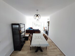 A compact living space with a dining area, a sofa, a bookshelf, and a kitchen area. - Beachfront apartment with a terrace and ocean view (Marina Saidia)