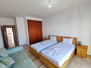 A hotel room with two beds, a wardrobe, a bedside table, and a sofa. - Beachfront apartment with a terrace and ocean view (Marina Saidia)