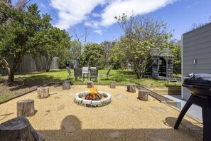 A backyard with a fire pit, outdoor furniture, and a barbecue grill. - The Sandman (McCrae)
